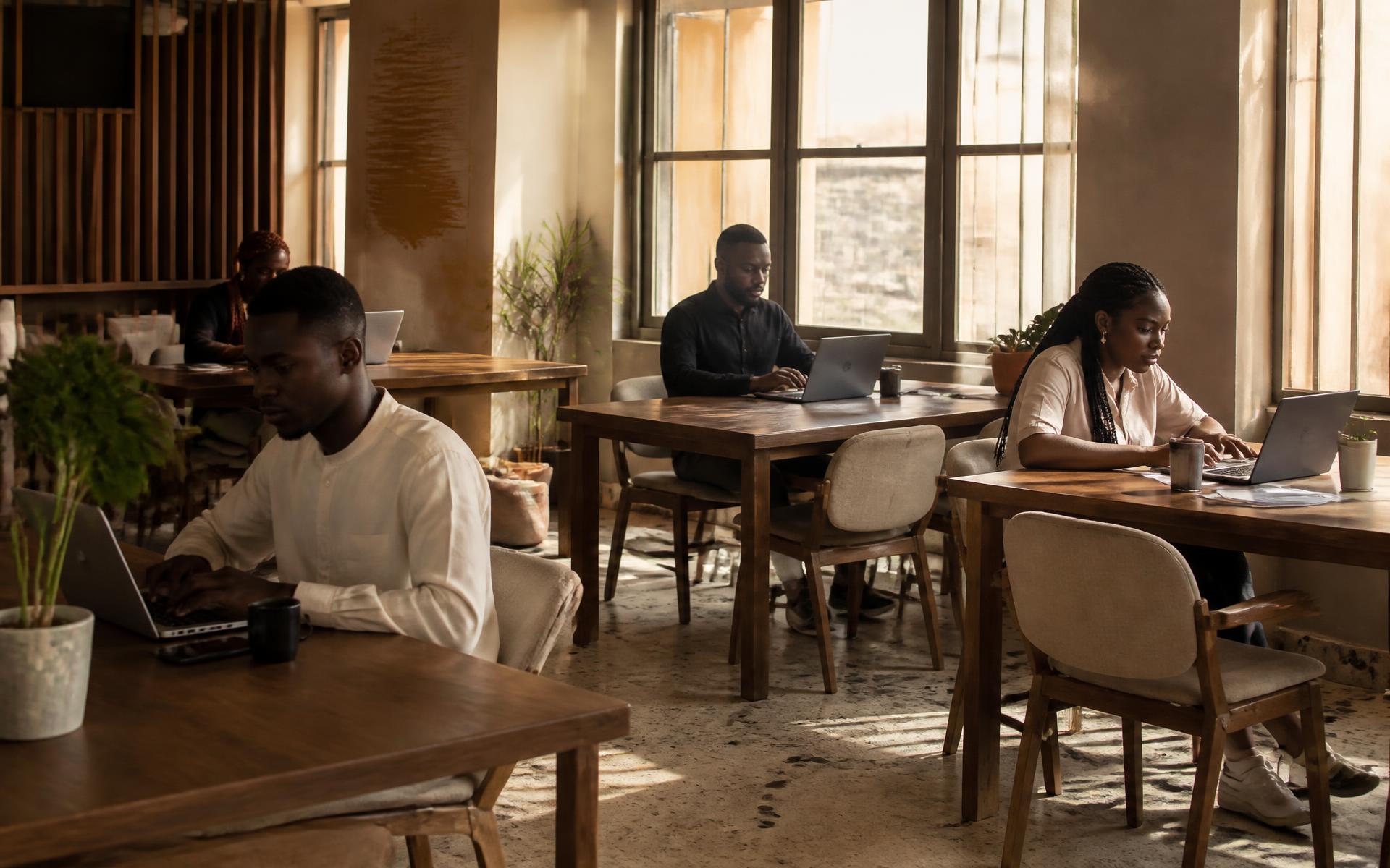 People working quietly at wooden desks in the daylit coworking area at The Cubicle in Ibadan